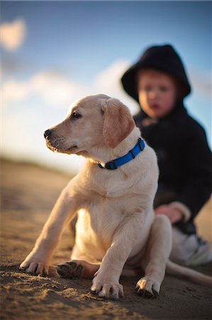 daycare borders - Boy and his dog sit on the beach. Stock Photo - Premium Royalty-Free, Code: 6128-08780568