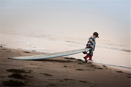 Little boy dragging surfboard into the sea. Stock Photo - Premium Royalty-Free, Code: 6128-08780573