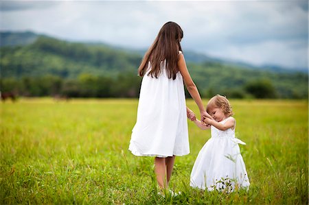 Young girl playing on rural field with her baby sister. Stock Photo - Premium Royalty-Free, Code: 6128-08780767