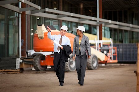 Two smiling engineers discussing plans on a construction site. Stock Photo - Premium Royalty-Free, Code: 6128-08780847