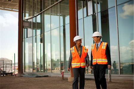 Two smiling engineers discussing plans on a construction site. Stock Photo - Premium Royalty-Free, Code: 6128-08780848