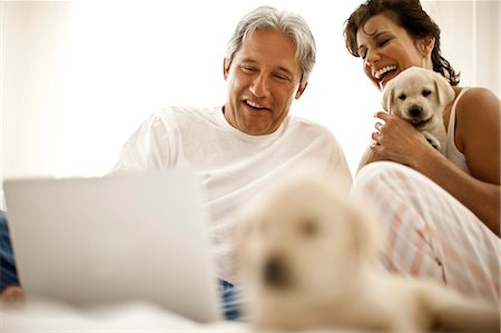 simsearch:6128-08738334,k - Couple holding puppies look at a laptop screen. Stock Photo - Premium Royalty-Free, Code: 6128-08780861