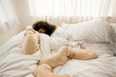 Woman lying in bed with puppies. Stock Photo - Premium Royalty-Free, Code: 6128-08780867
