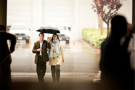 simsearch:6128-08738334,k - Happy mid adult couple walking together under an umbrella on a rainy day in the city. Stock Photo - Premium Royalty-Free, Code: 6128-08780834