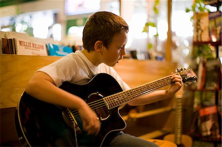 simsearch:649-07063808,k - Young boy strumming an acoustic guitar inside a music shop. Stock Photo - Premium Royalty-Free, Code: 6128-08798740