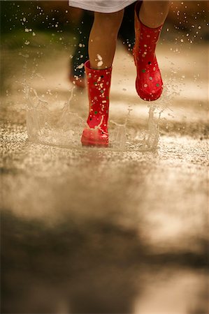 puddle in the rain - Red gumboots splashing through a rain puddle. Stock Photo - Premium Royalty-Free, Code: 6128-08798826