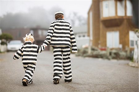 simsearch:614-06442834,k - Boy holding hands with his younger brother,  both wearing prisoner costumes Photographie de stock - Premium Libres de Droits, Code: 6128-08727438