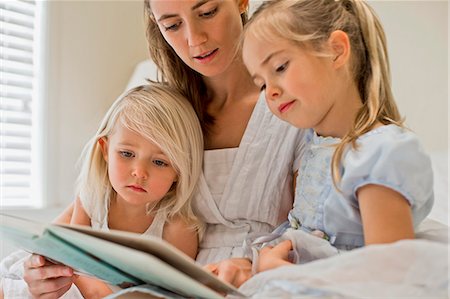 simsearch:614-06896931,k - Mother sitting on a bed reading a book with her daughters. Photographie de stock - Premium Libres de Droits, Code: 6128-08727515