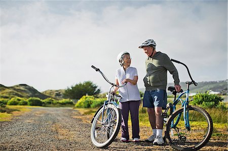 Happy elderly couple chat together as they take a break from biking along a country road. Stock Photo - Premium Royalty-Free, Code: 6128-08727792