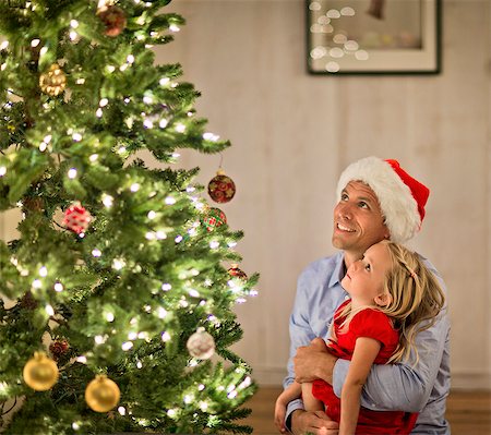 Father and daughter admiring the Christmas tree. Stock Photo - Premium Royalty-Free, Code: 6128-08728311