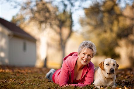 simsearch:700-00071488,k - Portrait of a smiling senior woman lying on her front in a field with her dog. Stock Photo - Premium Royalty-Free, Code: 6128-08737566