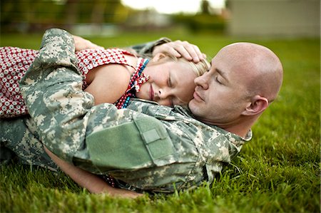 soldier with family - Male soldier hugging his young daughter while lying on the grass in their back yard. Photographie de stock - Premium Libres de Droits, Code: 6128-08737866