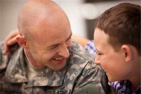 soldier with family - Mid adult man dressed in a military uniform is greeted by his son. Photographie de stock - Premium Libres de Droits, Code: 6128-08737868