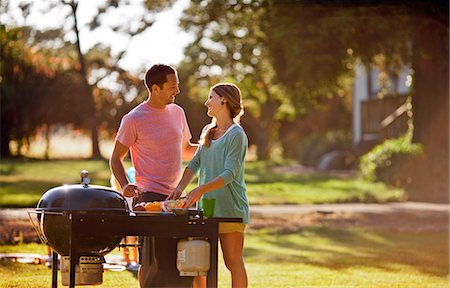 Smiling couple cooking on a barbecue in their back yard. Stock Photo - Premium Royalty-Free, Code: 6128-08737881