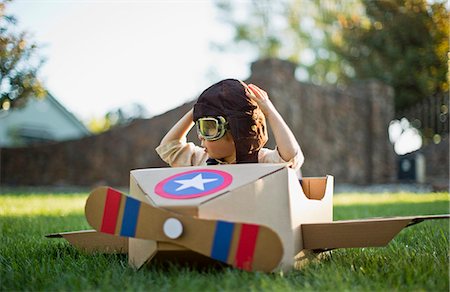 playing with toys - Young boy having fun pretending to be a pilot in a cardboard plane. Stock Photo - Premium Royalty-Free, Code: 6128-08738009