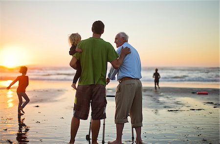 Senior man with a walking aid on the beach with his son and grandchild. Photographie de stock - Premium Libres de Droits, Code: 6128-08738131