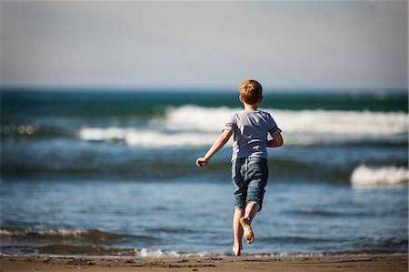 simsearch:649-07761212,k - Boy running towards the ocean on a sandy beach. Stock Photo - Premium Royalty-Free, Code: 6128-08738246