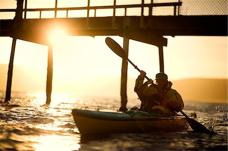 sit on dock - Young boy being shown how to paddle a kayak by his father in the ocean at sunset. Stock Photo - Premium Royalty-Free, Code: 6128-08738310