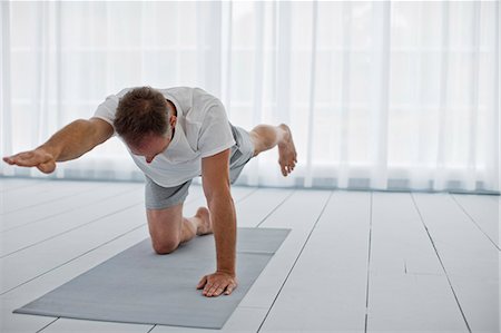 simsearch:6128-08825413,k - Middle aged man stretching his arms and legs while practicing yoga. Stock Photo - Premium Royalty-Free, Code: 6128-08738446