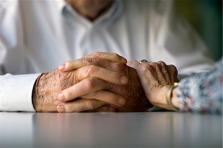 Elderly woman lays a comforting hand on her husband's arm. Stock Photo - Premium Royalty-Free, Code: 6128-08738619