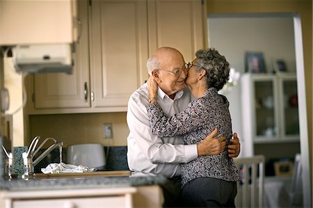 Affectionate elderly couple sneak a romantic kiss in the kitchen. Stock Photo - Premium Royalty-Free, Code: 6128-08738622