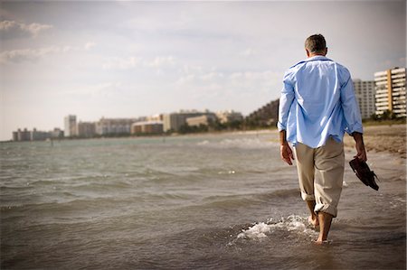 Mature adult man walking through the sea on a beach. Stock Photo - Premium Royalty-Free, Code: 6128-08840910