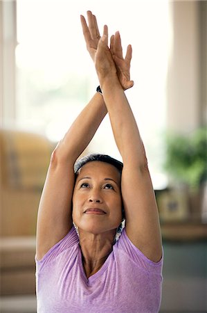 simsearch:6128-08825413,k - Woman stretches her arms above her head as she does yoga. Stock Photo - Premium Royalty-Free, Code: 6128-08841008