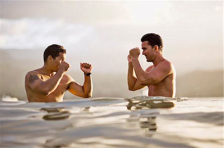 Two men challenge each other in a boxing pose as they stand in the sea. Stock Photo - Premium Royalty-Free, Code: 6128-08825365