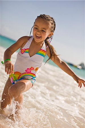 Laughing young girl in a swimsuit playing in the waves at a beach. Stock Photo - Premium Royalty-Free, Code: 6128-08825448