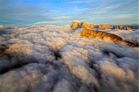 sunset mountains - Aerial shot from Seceda of Odle surrounded by clouds at sunset. Dolomites Val Funes Trentino Alto Adige South Tyrol Italy Europe Stock Photo - Premium Royalty-Free, Code: 6129-09058138