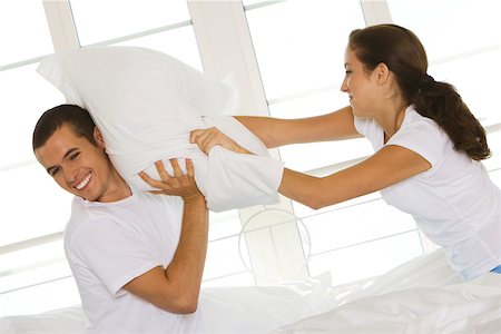 simsearch:625-00839074,k - Side profile of a young couple having a pillow fight Stock Photo - Premium Royalty-Free, Code: 625-00839056
