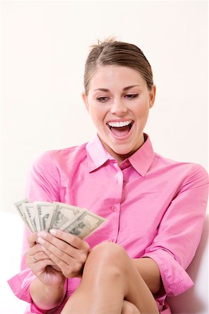 Young woman holding US paper currency and laughing Stock Photo - Premium Royalty-Free, Code: 625-00839379