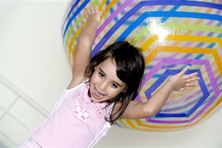 Close-up of a girl holding a large inflatable ball over her head Stock Photo - Premium Royalty-Free, Code: 625-00841710