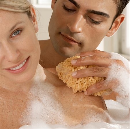 Close-up of a young man scrubbing a young woman's shoulder with a bath sponge Stock Photo - Premium Royalty-Free, Code: 625-00900292