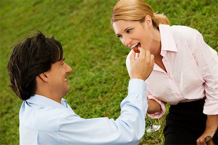 Side profile of a businessman feeding a  cherry to a businesswoman Foto de stock - Sin royalties Premium, Código: 625-00901095