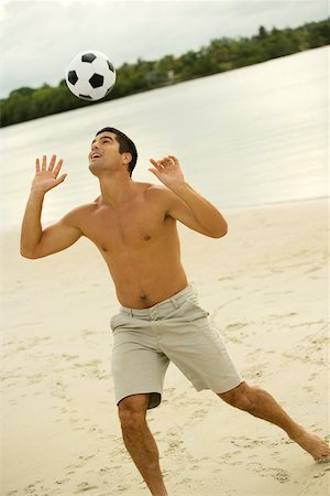 football ball american - Mid adult man heading a soccer ball on the beach Stock Photo - Premium Royalty-Free, Code: 625-00901417