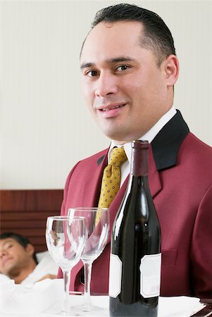 Portrait of a waiter holding a tray with a wine bottle and two wineglasses Stock Photo - Premium Royalty-Free, Code: 625-01038798