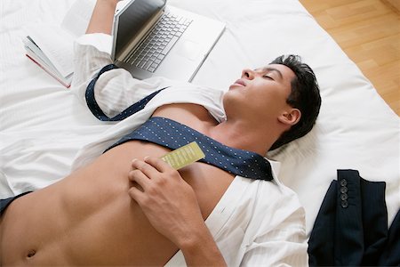 High angle view of a businessman sleeping on the bed Stock Photo - Premium Royalty-Free, Code: 625-01038984