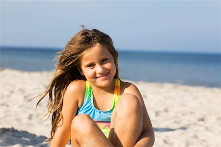 Portrait of a girl sitting on the beach and smiling Stock Photo - Premium Royalty-Free, Code: 625-01094003