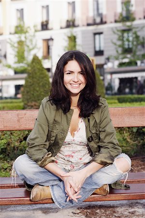 Portrait of a mid adult woman sitting on a park bench and smiling Stock Photo - Premium Royalty-Free, Code: 625-01096529