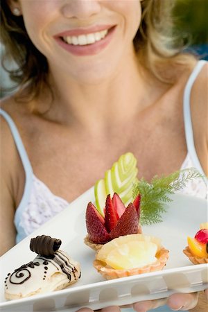 simsearch:625-01250196,k - Close-up of a young woman holding assorted tarts with an eclair in a platter Stock Photo - Premium Royalty-Free, Code: 625-01097523