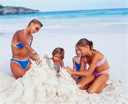 Close-up of a mid adult woman with her three daughters making a castle on the beach, Bermuda Stock Photo - Premium Royalty-Free, Code: 625-01092046