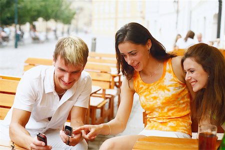 simsearch:6115-06733060,k - Young man holding two mobile phones with two young women sitting beside him Foto de stock - Sin royalties Premium, Código: 625-01092584
