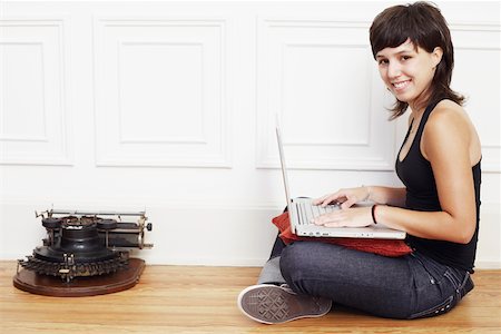 Portrait of a young woman sitting on the floor and using a laptop Stock Photo - Premium Royalty-Free, Code: 625-01093129