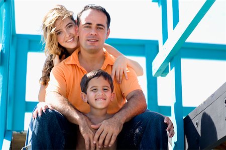 Portrait of a mid adult man and a young woman sitting with their son in a lifeguard hut Stock Photo - Premium Royalty-Free, Code: 625-01250392