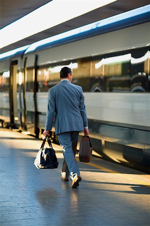 Rear view of a man walking at a railroad station platform, Rome, Italy Stock Photo - Premium Royalty-Free, Code: 625-01250640