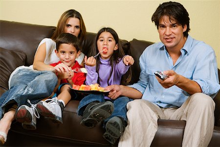 Mid adult couple with their children sitting on a couch and watching television Stock Photo - Premium Royalty-Free, Code: 625-01250823