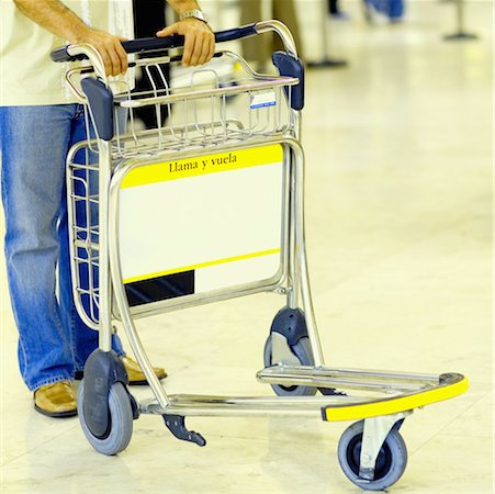 Close-up of a person standing with a luggage cart Stock Photo - Premium Royalty-Free, Code: 625-01250965