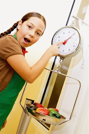 Portrait of a girl pointing at a weight scale and looking surprised Stock Photo - Premium Royalty-Free, Code: 625-01251294