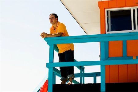 Low angle view of a mid adult man leaning against a railing of a lifeguard hut Stock Photo - Premium Royalty-Free, Code: 625-01251982